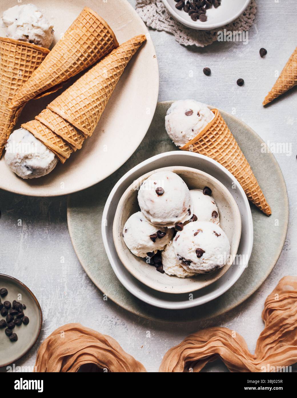 Delicious banana ice cream scoops with chocolate chips are served in crispy waffle cones. Ingredients include Greek yogurt and ripe bananas, offering Stock Photo