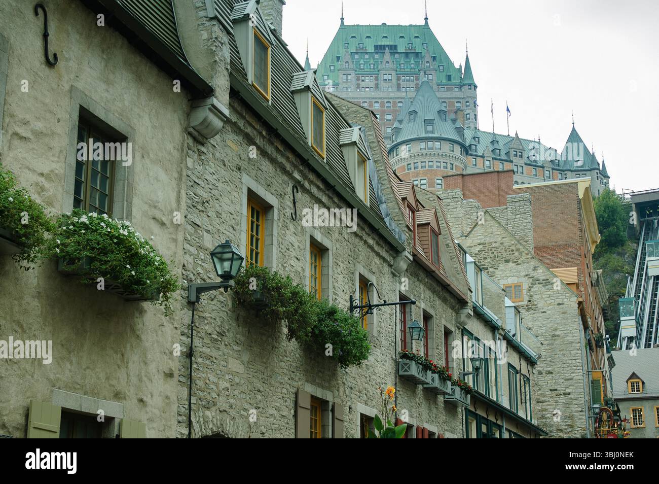Stone buildings with flower boxes line a historic Quebec street below ...