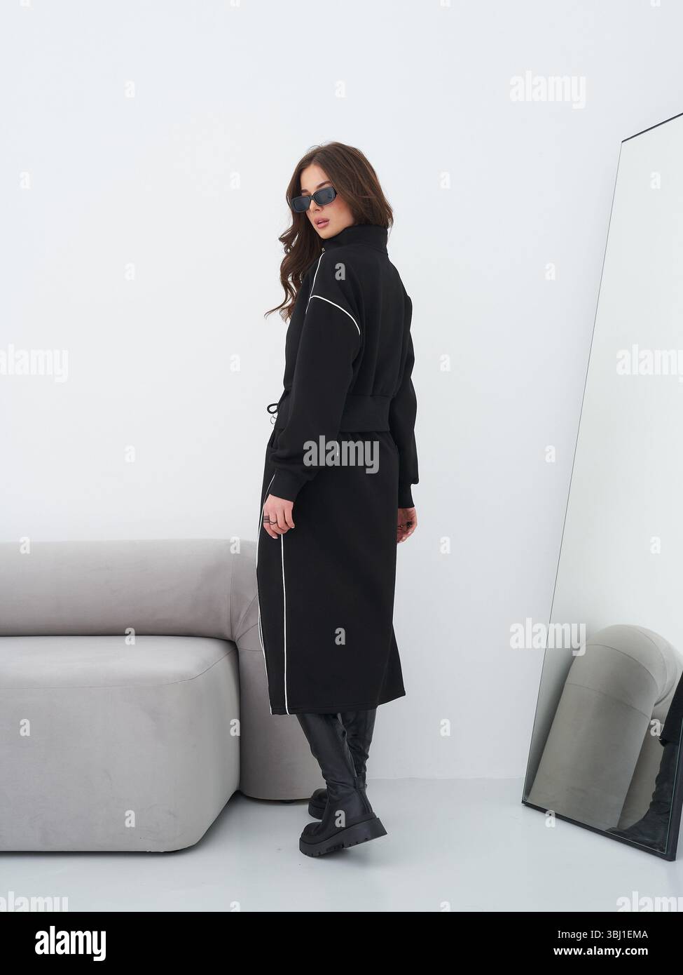 Brunette model showcases stylish black outfit in modern studio setting Stock Photo