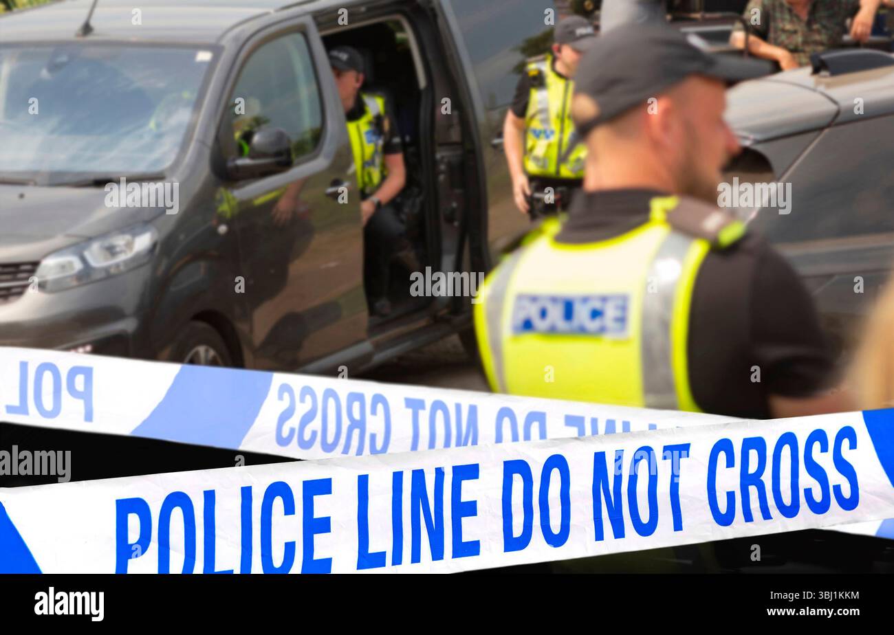 Police officers in uniform near a vehicle at scene with police line ...