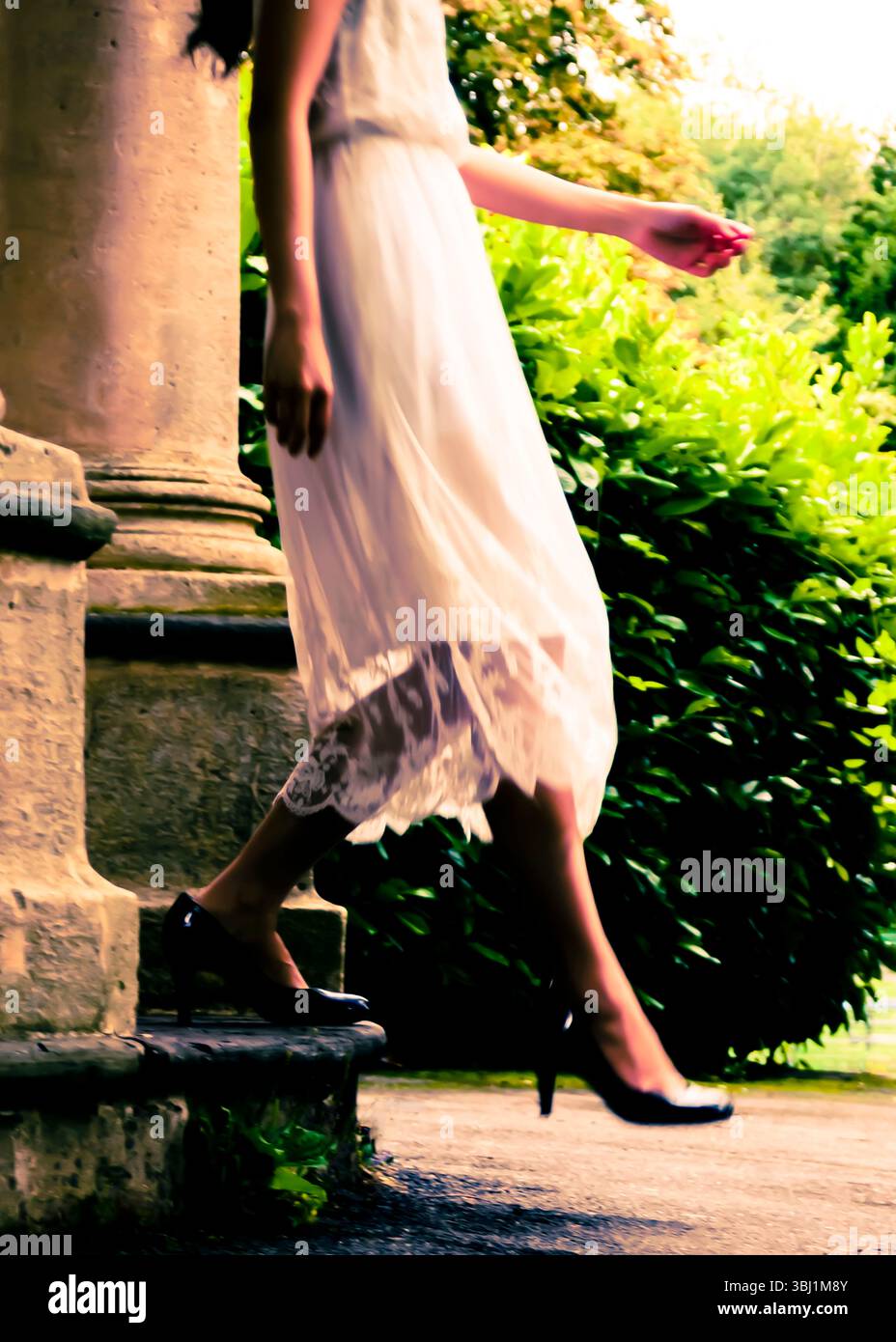 A woman in a white dress and black heels is walking down some steps ...