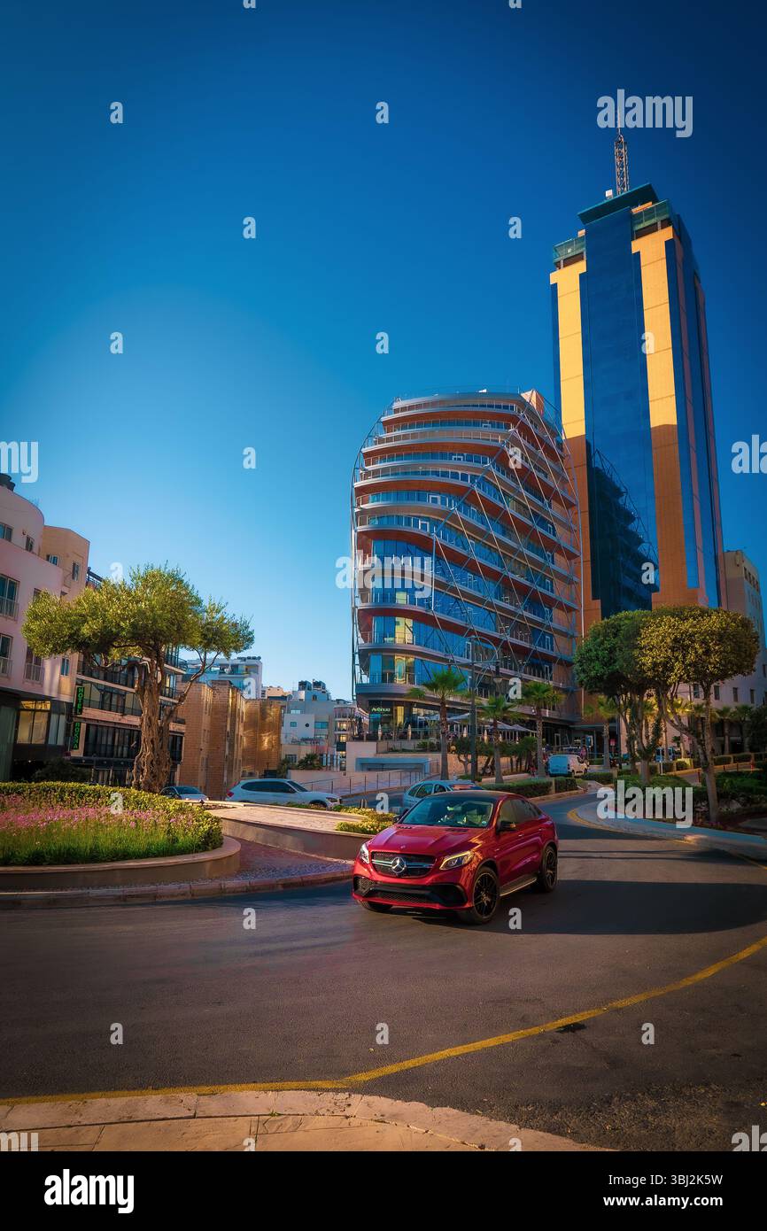 Scenic view of a Mercedes-Benz Sports Coupé driving around a roundabout in front of the Portomaso Business Tower in Saint Julian's (San Ġiljan), Malta Stock Photo