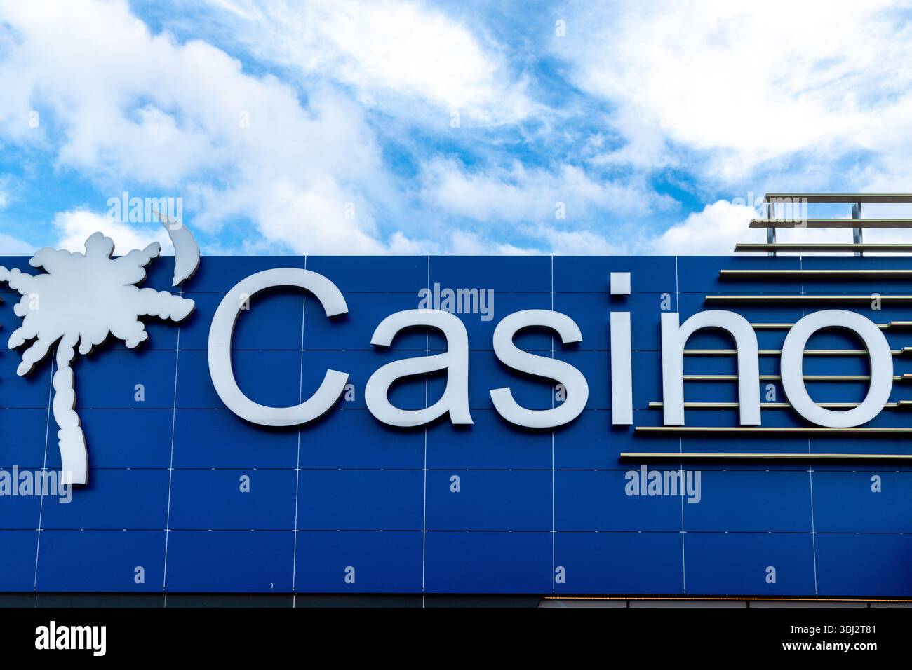 Denia, Alicante - Spain - 11-26-2024: A large white casino sign with a stylized palm tree logo is mounted on a modern blue building. The sky in the ba Stock Photo