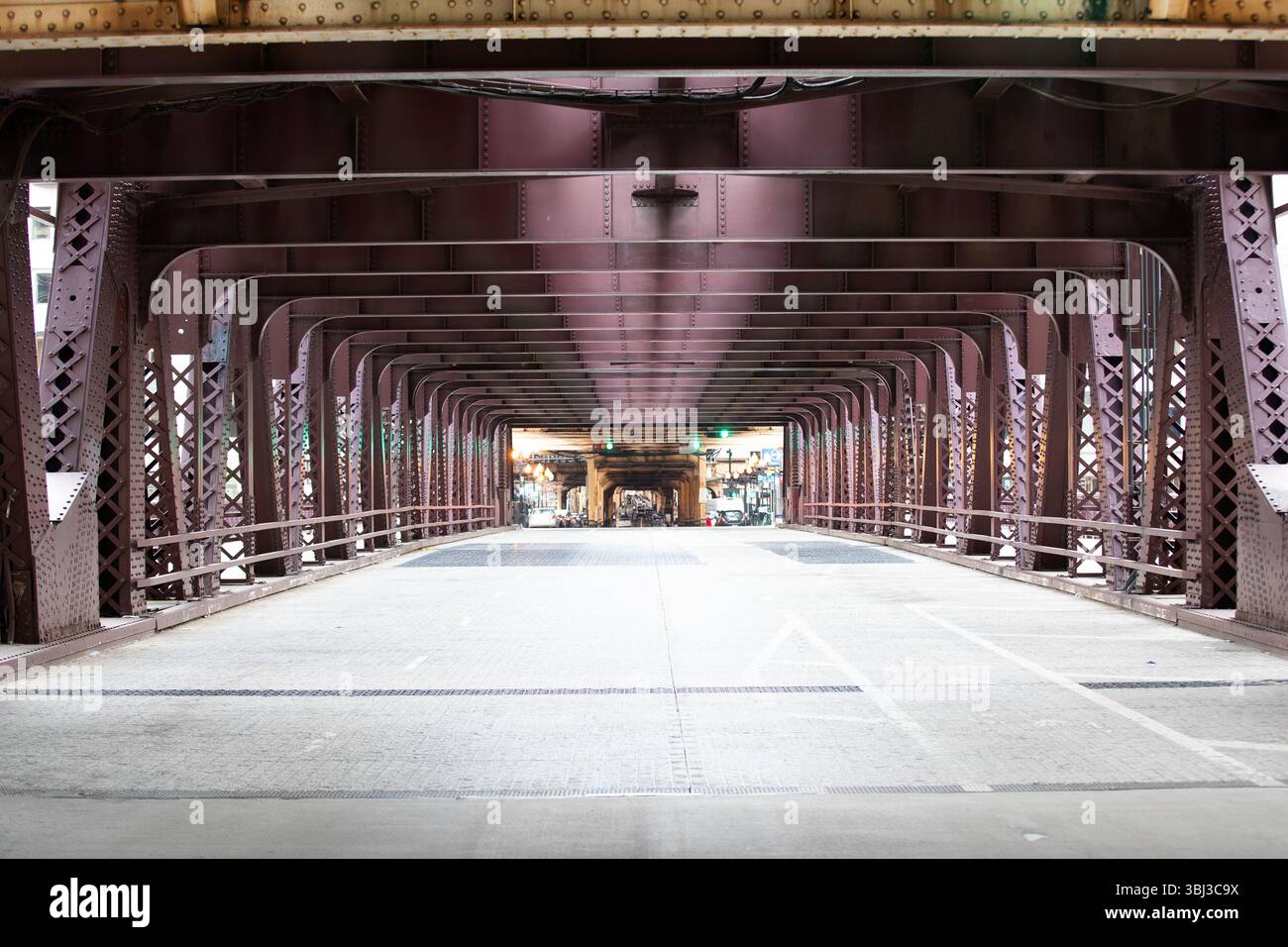 View down the symmetrical interior structure of an urban steel bridge, emphasizing architectural patterns and perspective in Chicago, Illinois Stock Photo