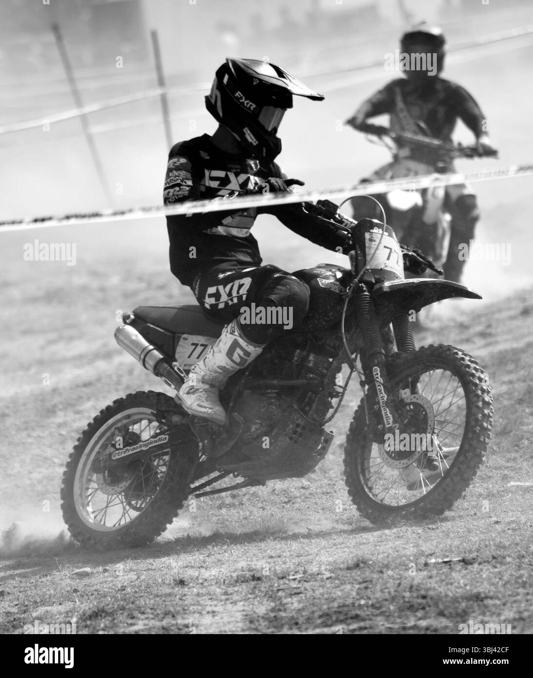 Motocross rider competing in a competition riding through a cloud of dirt, showing dedication and adrenaline rush Stock Photo