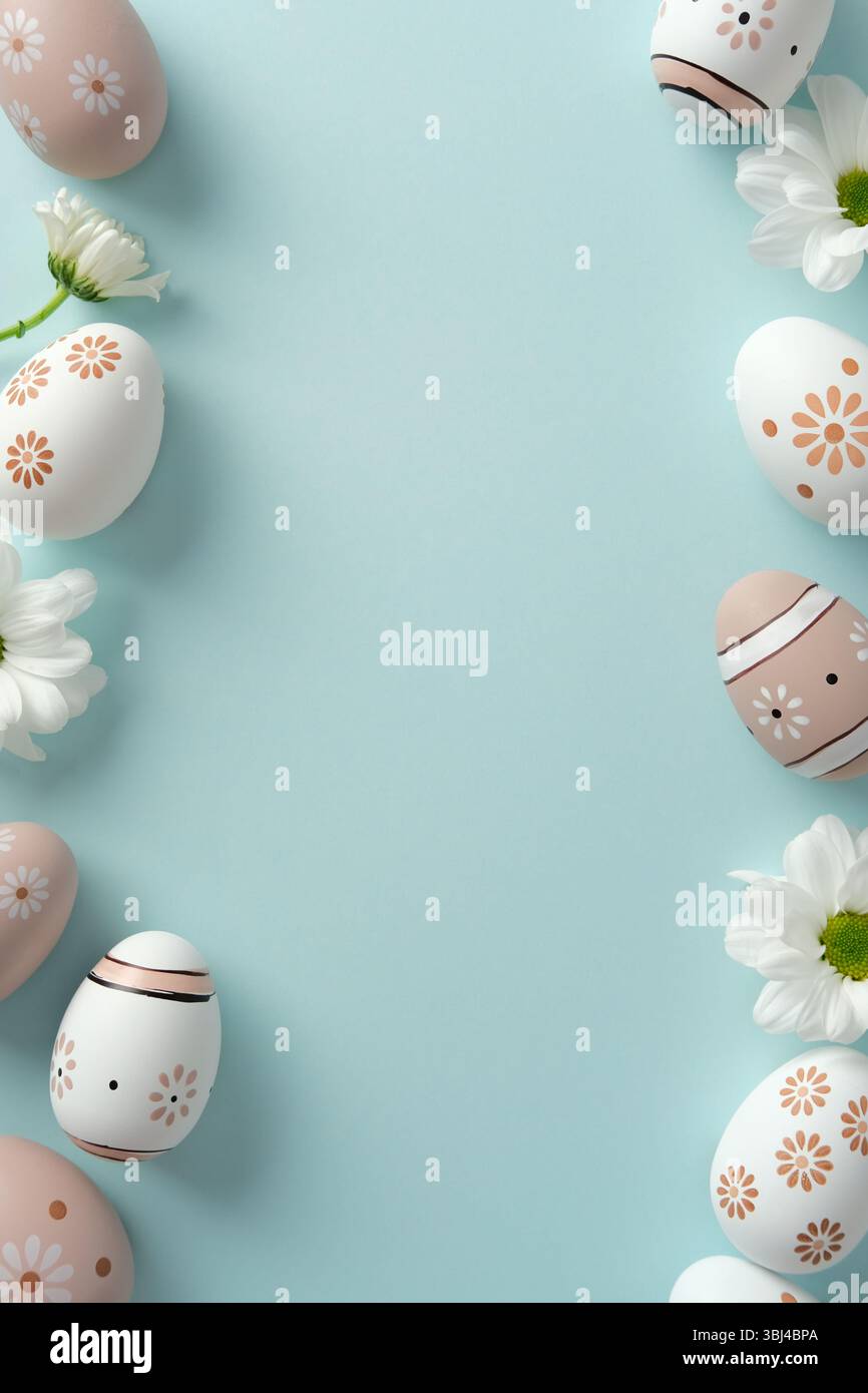 Pastel Easter eggs and white daisies on a light blue background Stock Photo