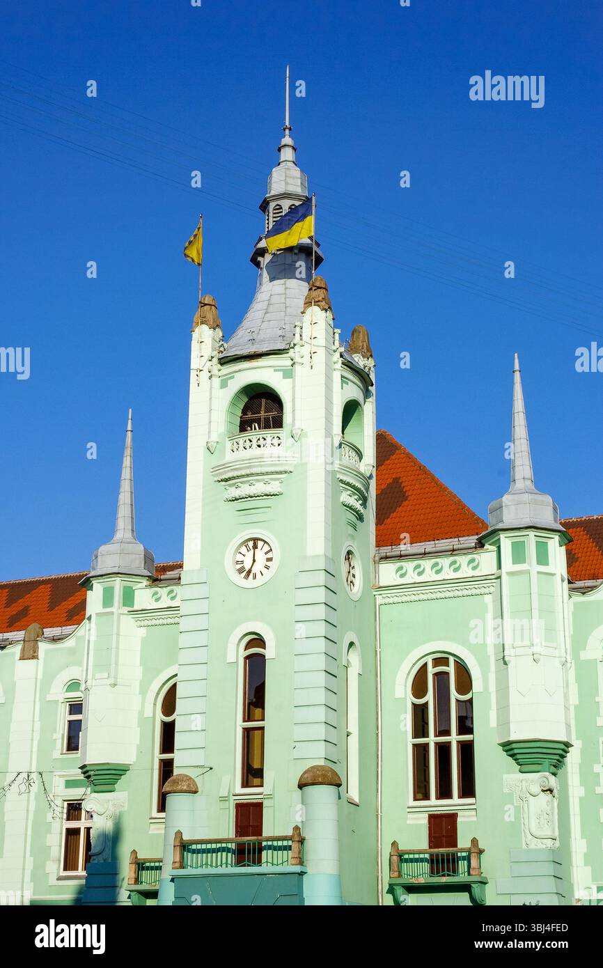 mukachevo, ukraine - jun 16 2012: city council of the old town in morning light. green building with clock tower. popular travel attraction in the cit Stock Photo