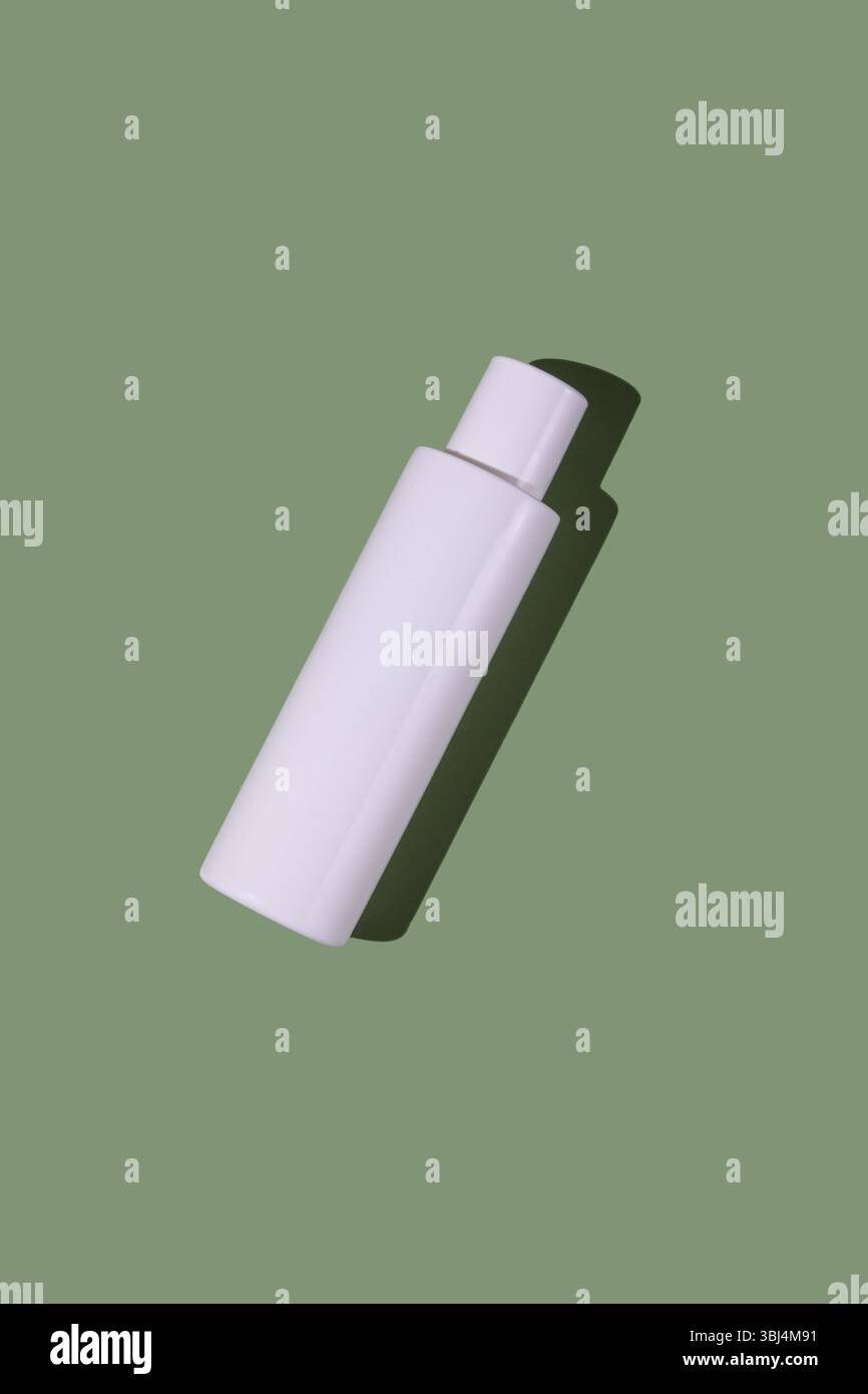 White transparent cosmetics plastic bottle, green background Stock Photo