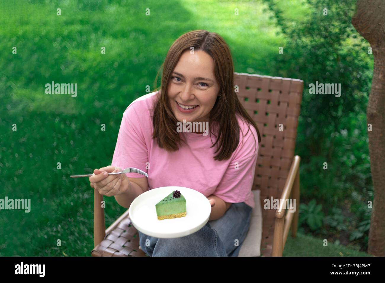 Woman in a pink t?shirt tasting a colored cake and smiling warmly Stock Photo