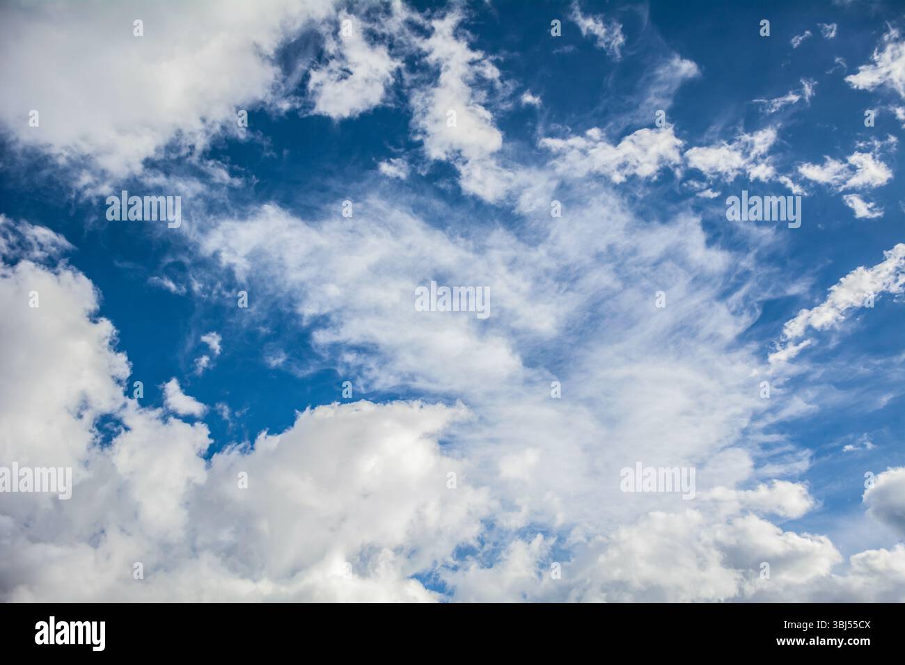 A serene sky with fluffy white clouds scattered across a bright blue ...