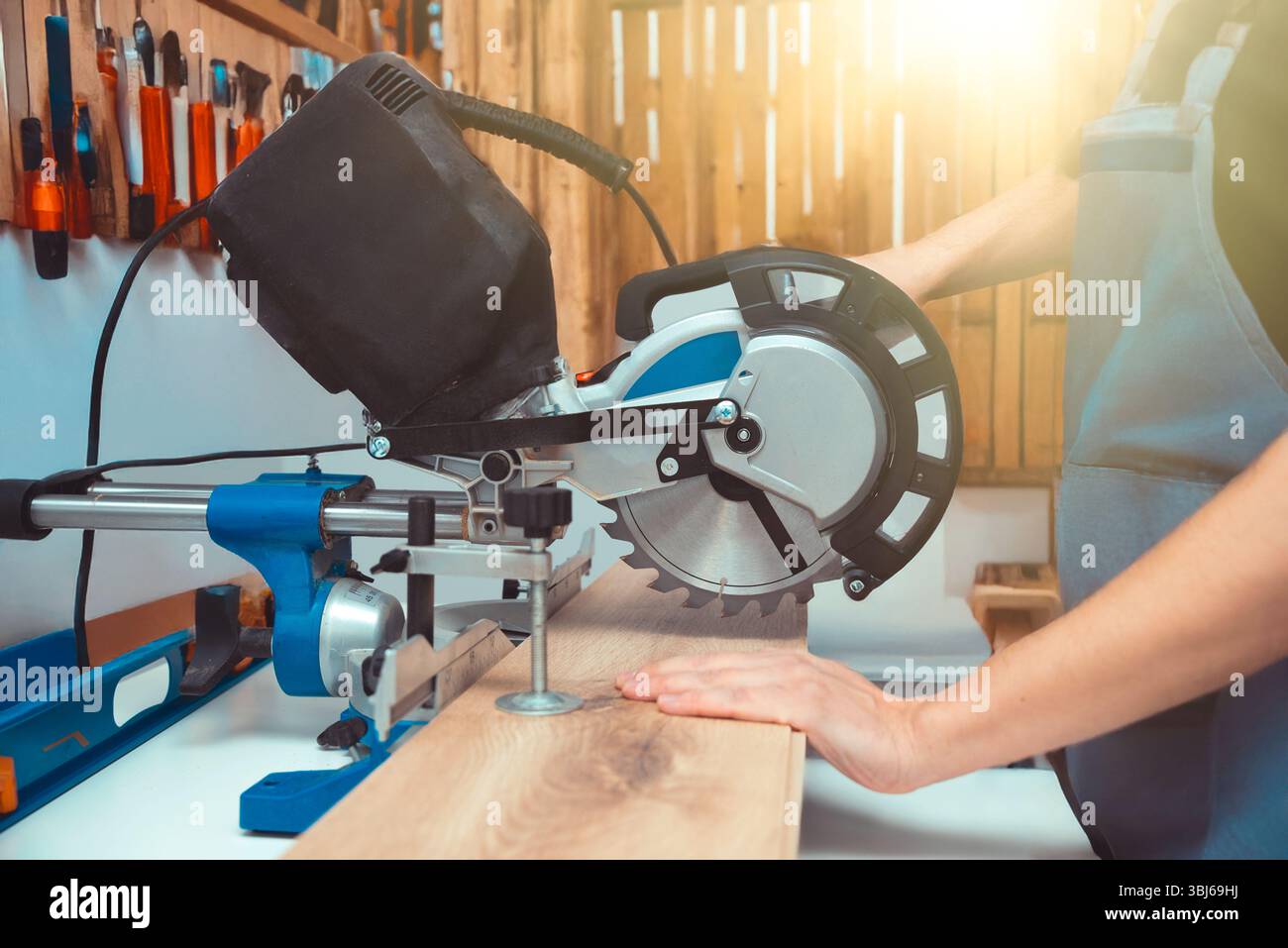 Carpenter using miter saw while working on flooring panels Stock Photo