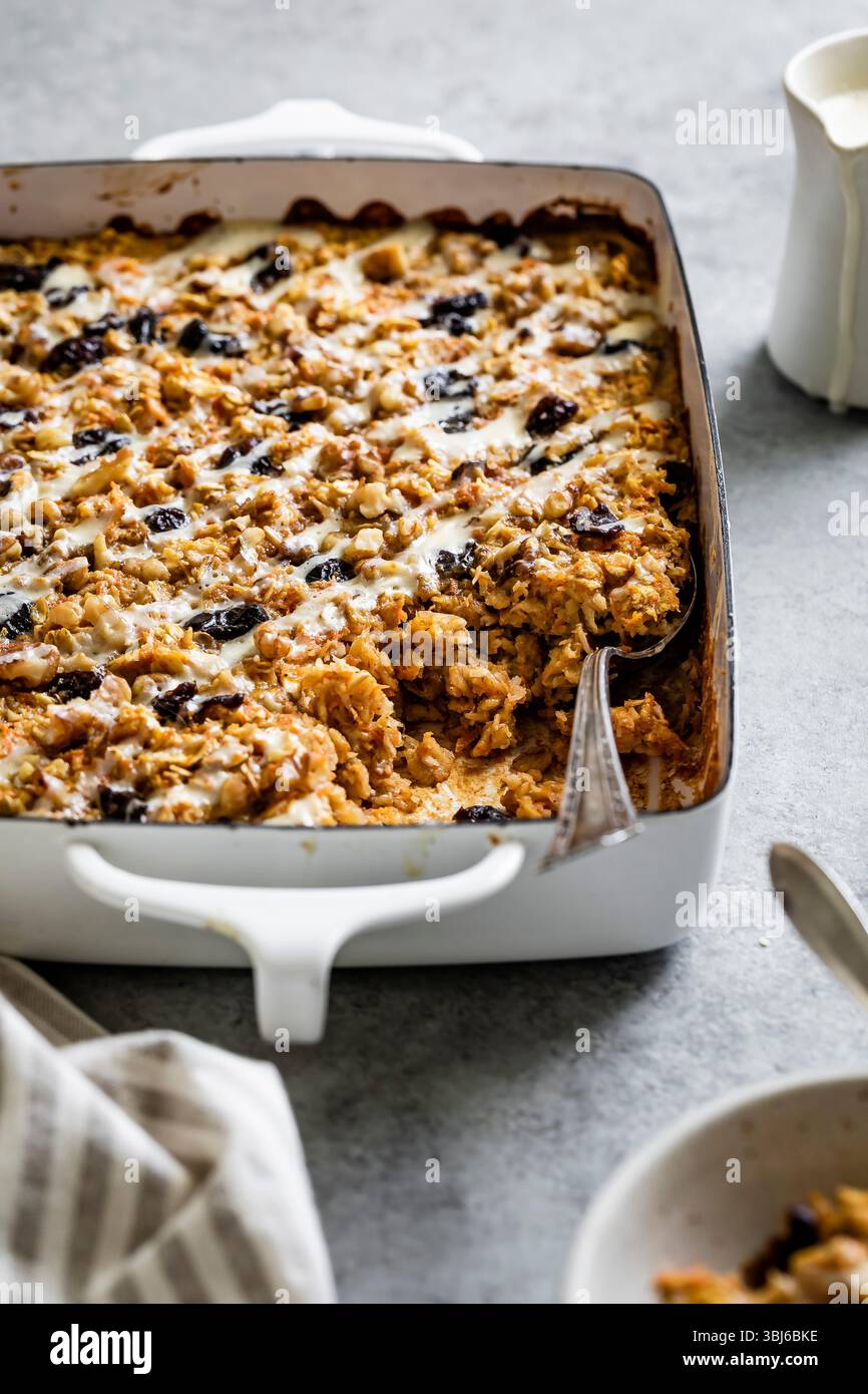 A baked oatmeal dish filled with nuts and dried fruits in a white casserole dish. Stock Photo