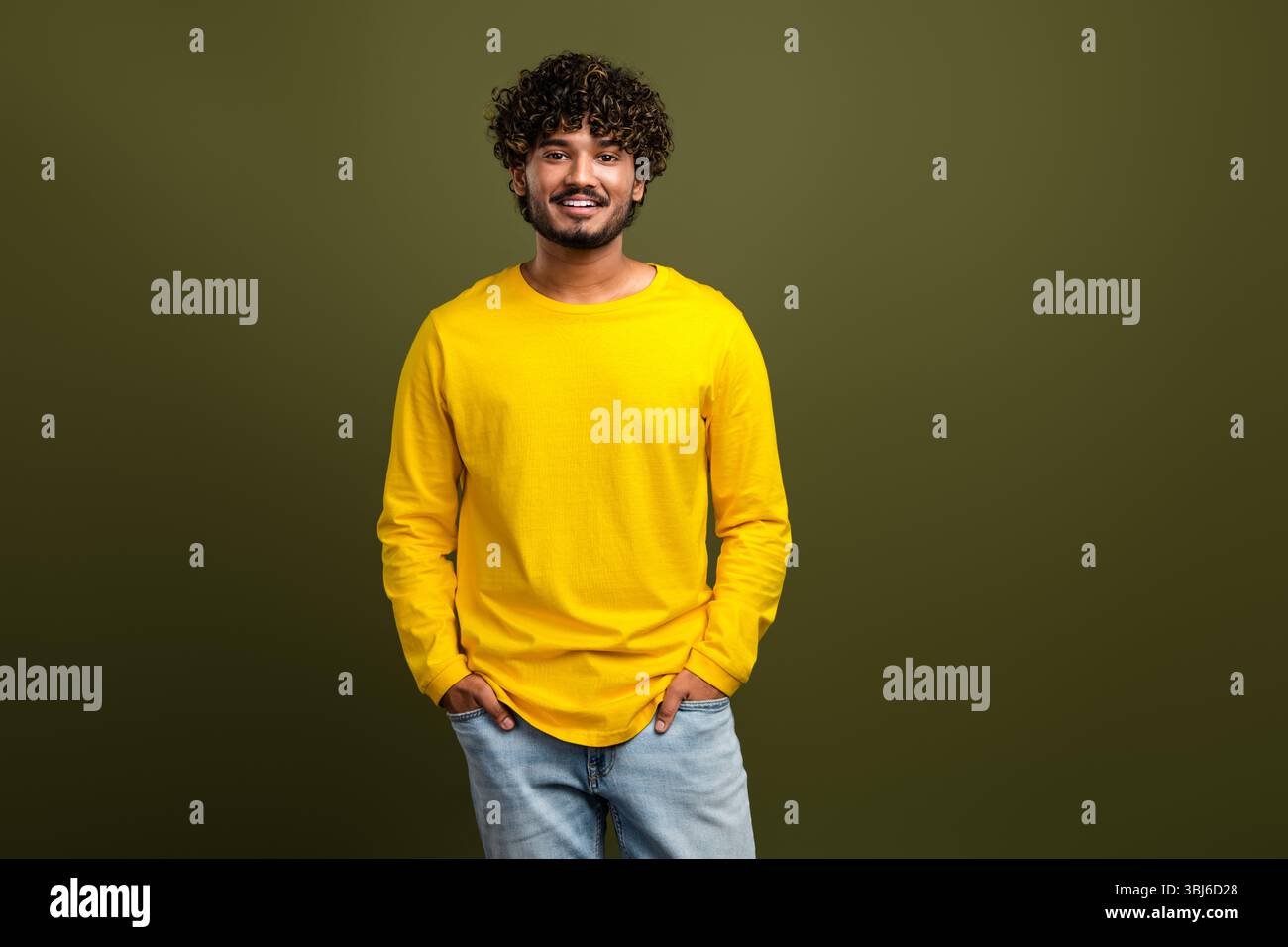 Portrait of a young man wearing a vibrant yellow shirt against a stylish khaki background, showcasing casual fashion Stock Photo