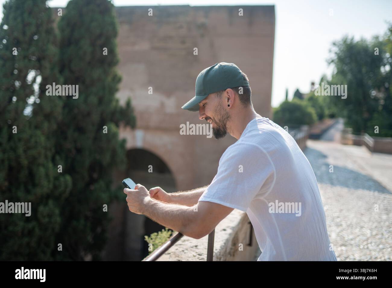 Smiling tourist using a smartphone and writing. Stock Photo