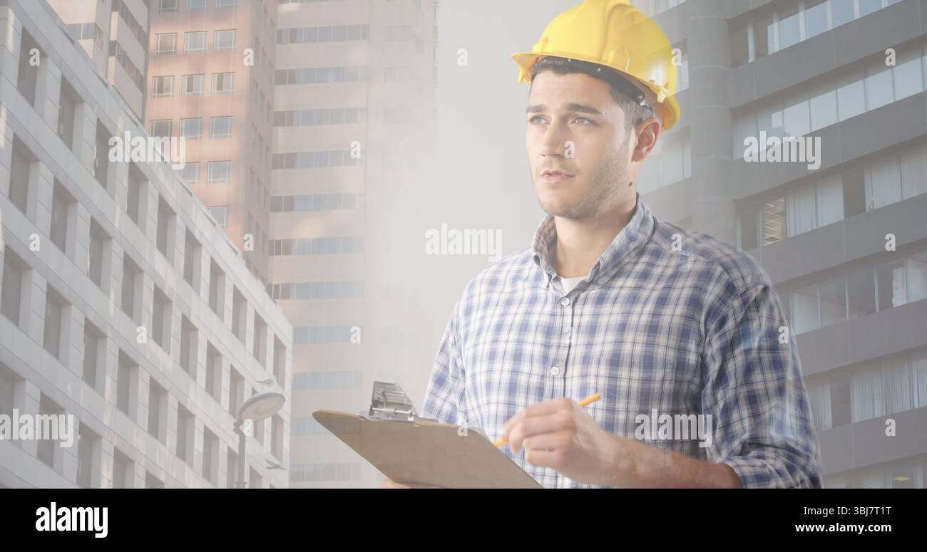Inspecting engineer wearing hard hat taking notes on clipboard in downtown construction Stock Photo