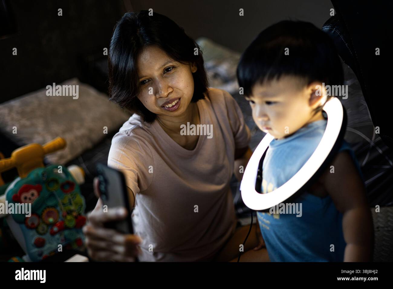 Mom And Toddler Plays With A Ring Light On His Neck, Background for advertising and wallpaper in walking and lifestyle scene. Stock Photo