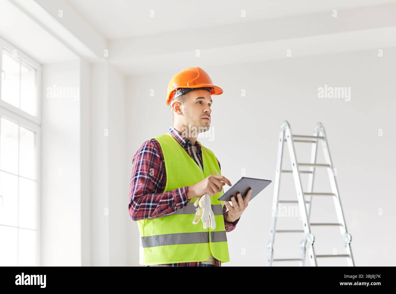 Worker Planning Renovation Using Tablet Pc And Blueprint At Home Stock Photo