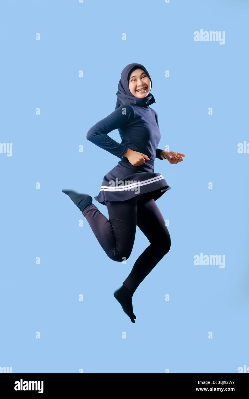 A woman in a black skirt is jumping in the air. She is smiling and she is happy Stock Photo