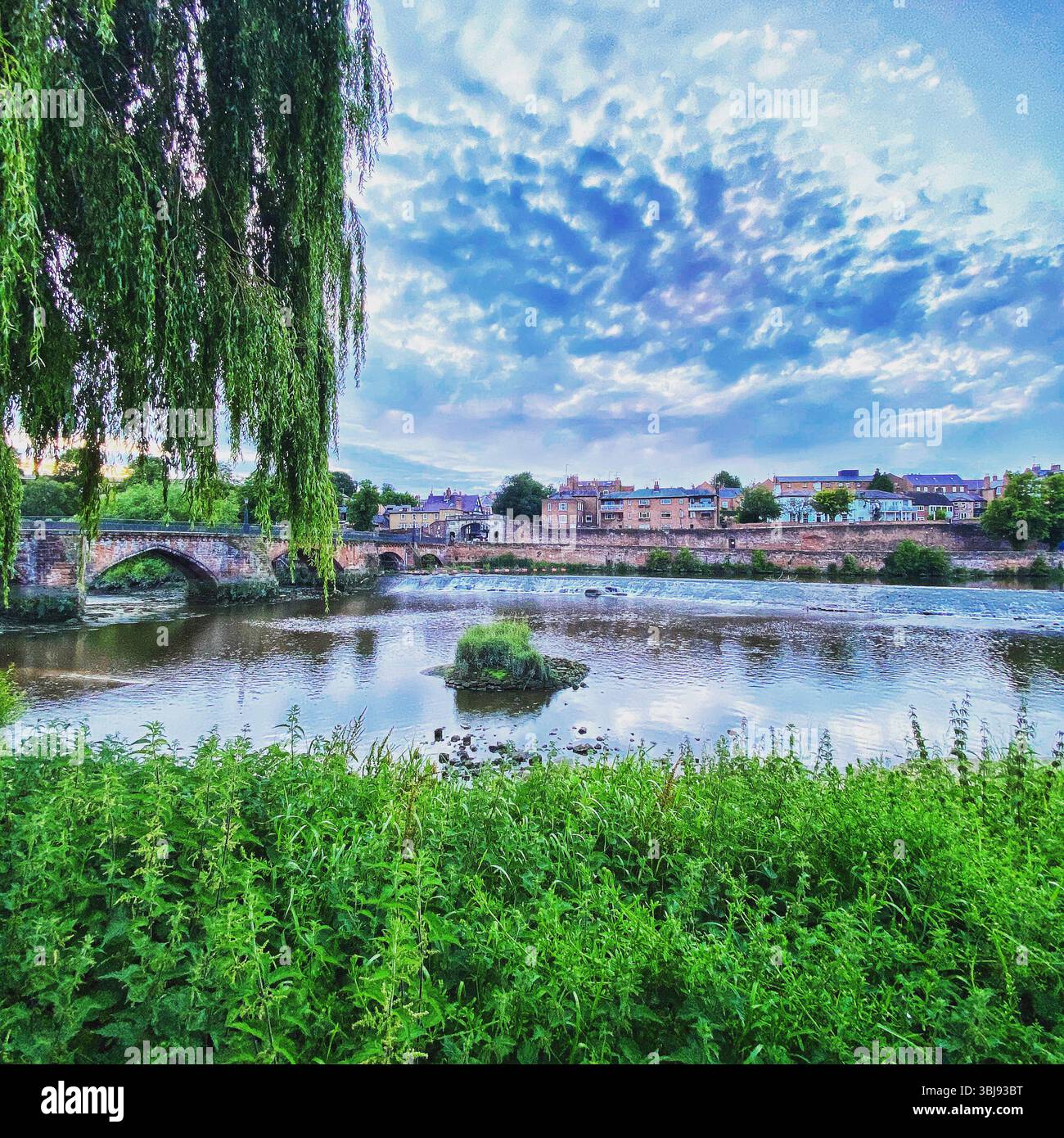 View of Chester cityscape from Handbridge, showing River Dee, city walls, historic buildings, and lush greenery, Cheshire, UK - Smartphone Captured Stock Image