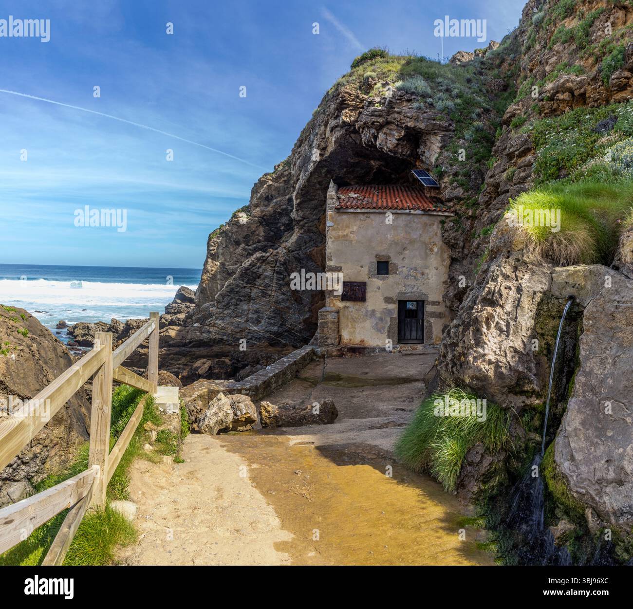 Ermita de Santa Justa, enclavada en un acantilado con vistas al mar Cantábrico.  Al fondo, las olas rompen contra las rocas. Ubiarco, España Stock Photo