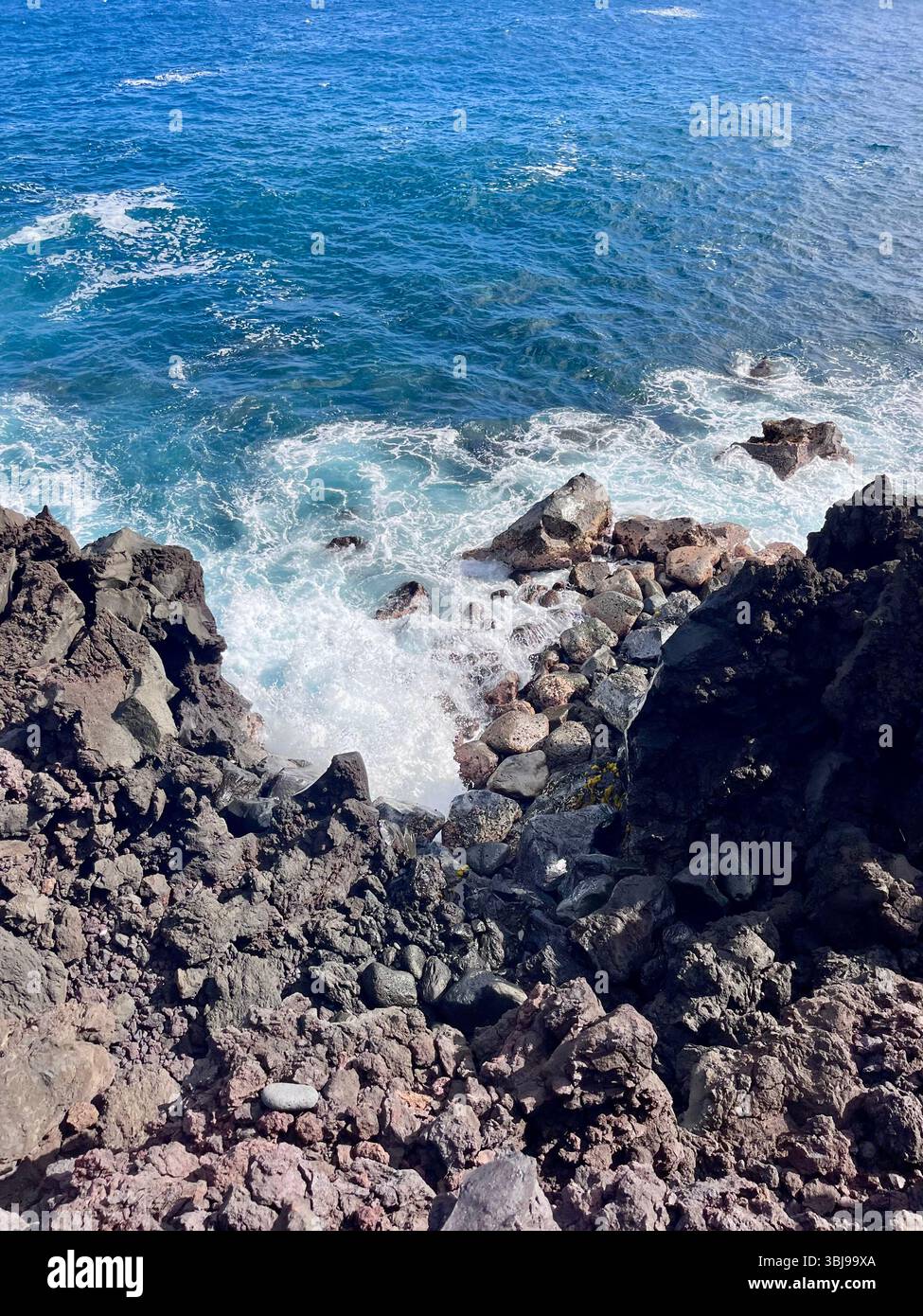 The beautiful and magical black sand beaches on the Big Island of Hawai'i, USA with volcanic black lava rock and crashing waves. - Smartphone Captured Stock Image