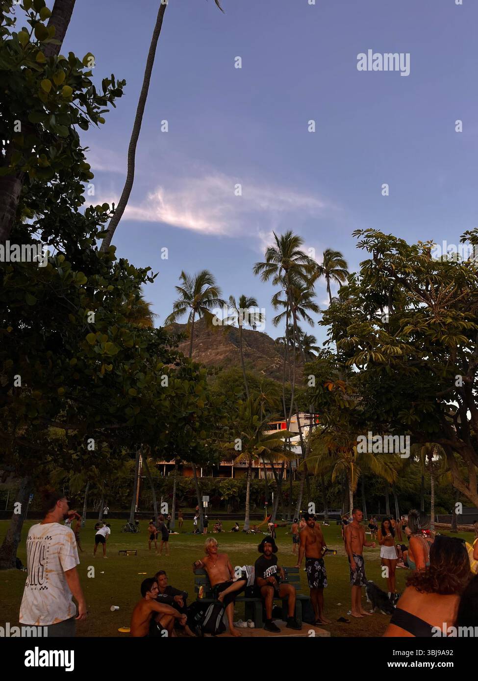 People socializing at Hawaii's Leahi Beach Park in the golden light of a Hawaiian sunset. - Smartphone Captured Stock Image