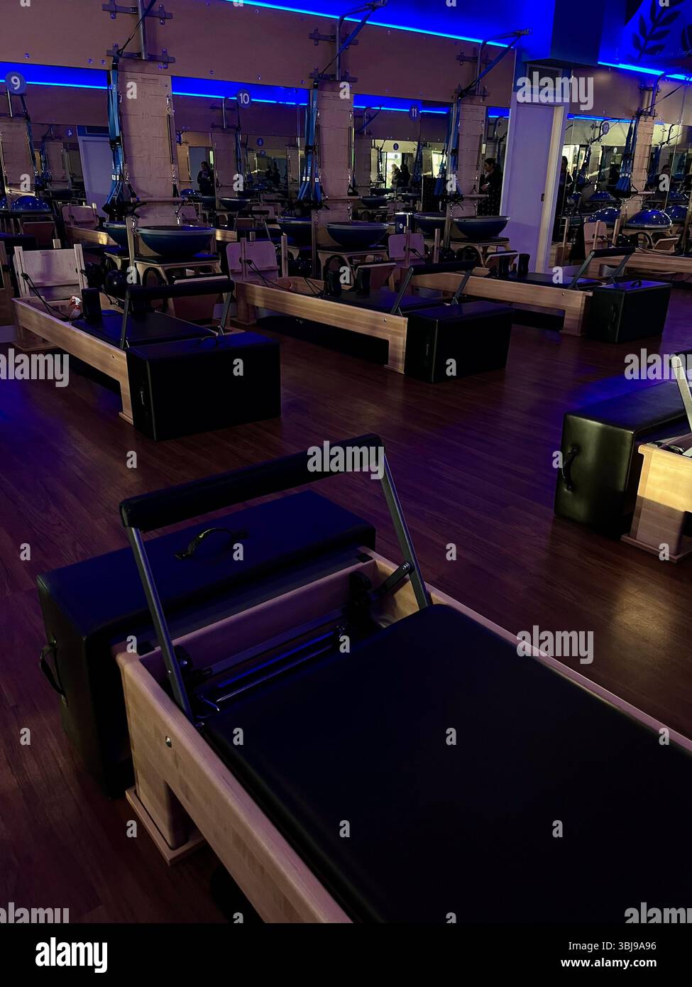 An aesthetic and dimly lit reformer Pilates studio equipped with reformer machines on the island of O'ahu, Hawai'i, USA. - Smartphone Captured Stock Image