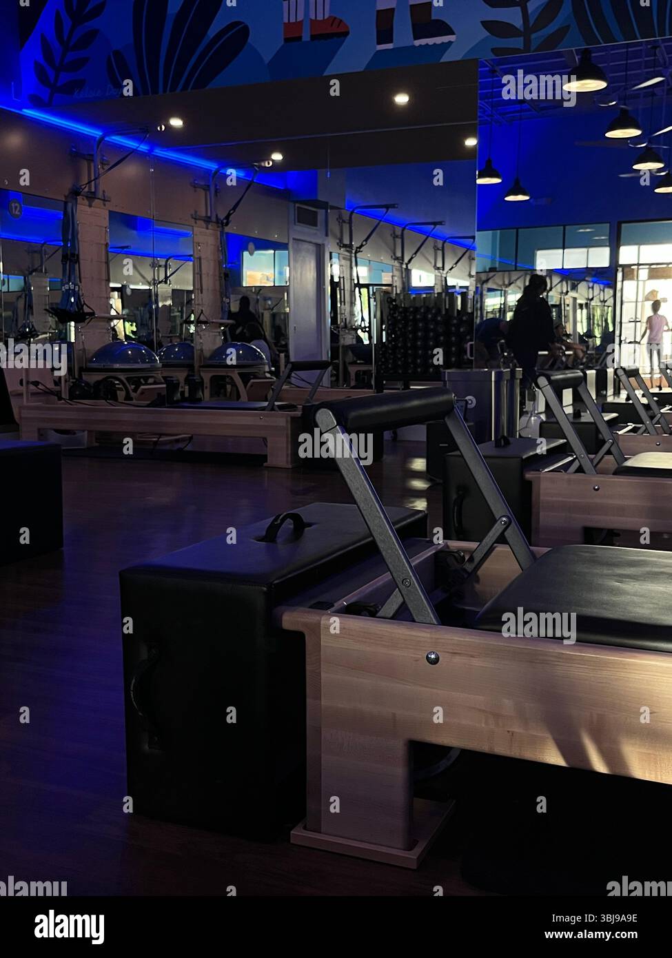 An aesthetic and dimly lit reformer Pilates studio equipped with reformer machines on the island of O'ahu, Hawai'i, USA. - Smartphone Captured Stock Image
