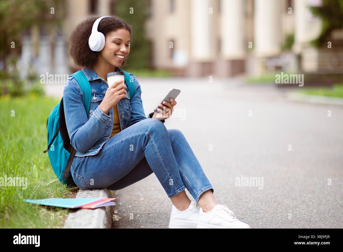 Happy Black Student Woman Using Smartphone And Drinking Coffee Outdoors Stock Photo
