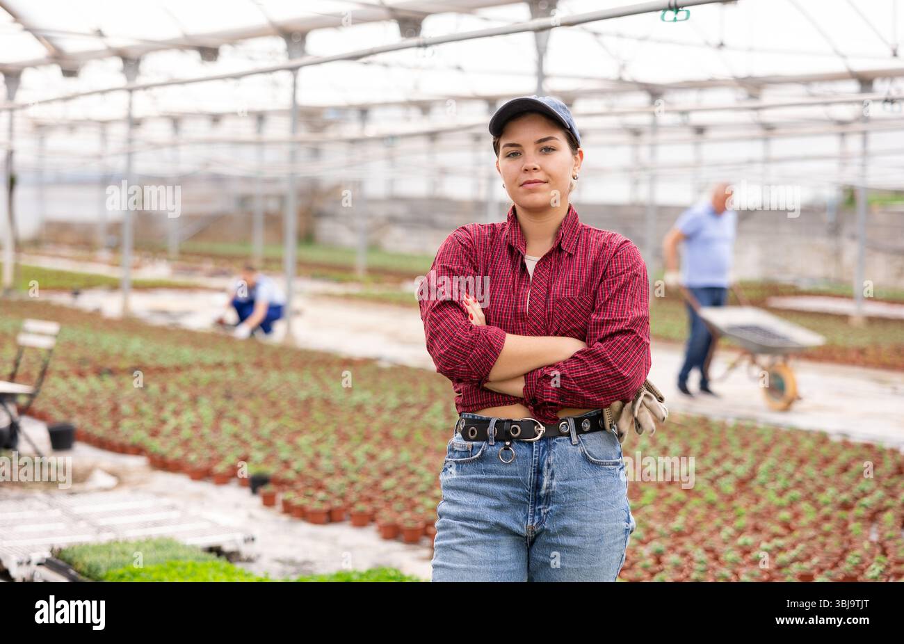 Young woman worker posing joyfully in greenhouse Stock Photo