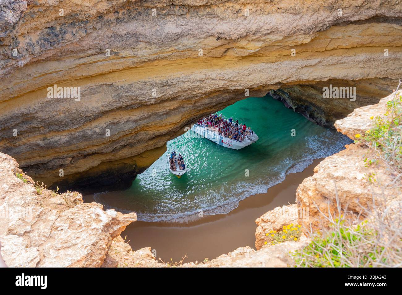Tourists visiting inside of Benagil Caves on the tour boats viewed through the hole from above. Stock Photo