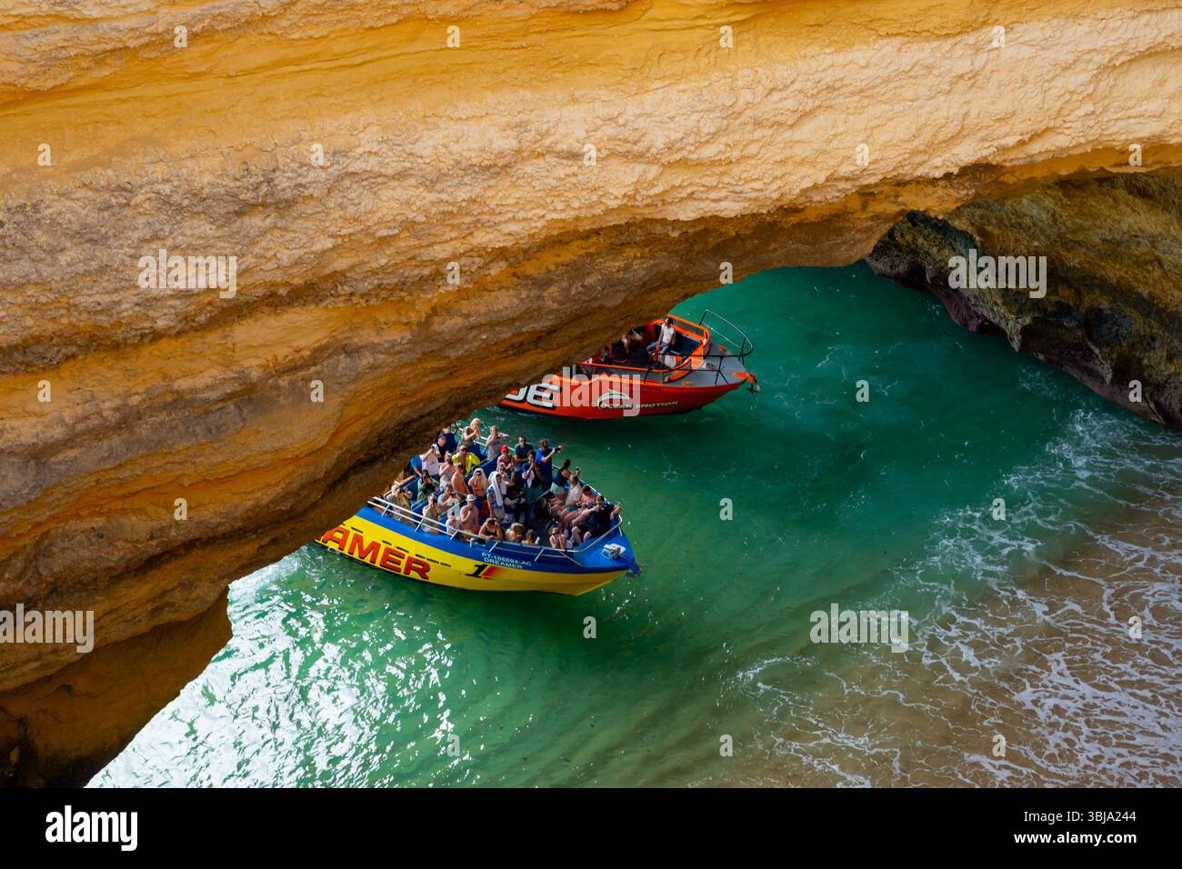 Tourists visiting inside of Benagil Caves on the tour boats viewed through the hole from above. Benagil, Algarve, Portugal. Stock Photo
