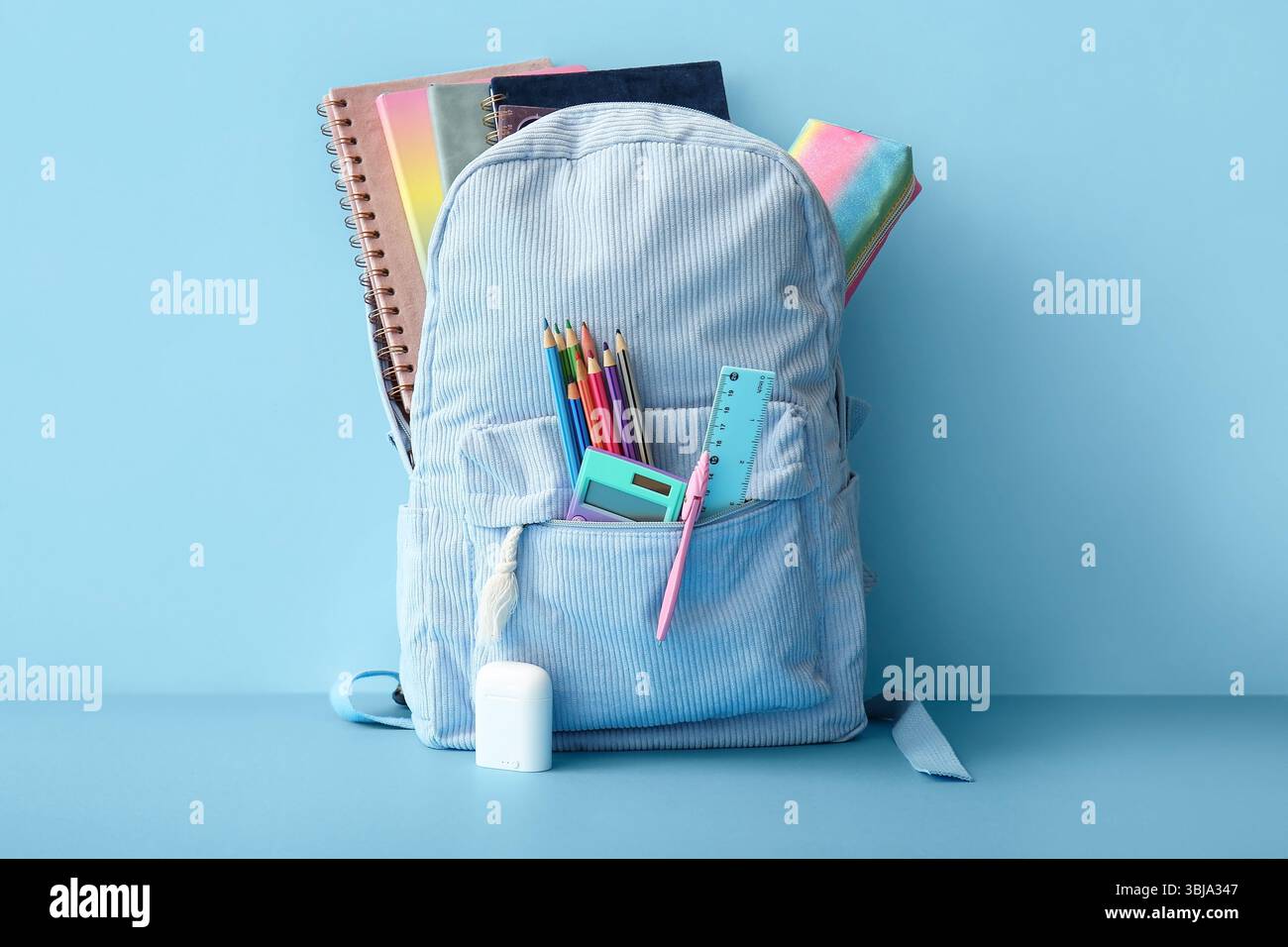 School backpack with different stationery on blue background Stock Photo