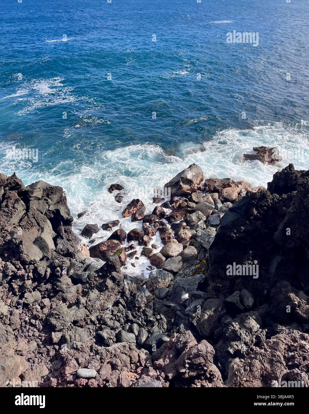 The beautiful and magical black sand beaches on the Big Island of Hawai'i, USA with volcanic black lava rock and crashing waves. - Smartphone Captured Stock Image