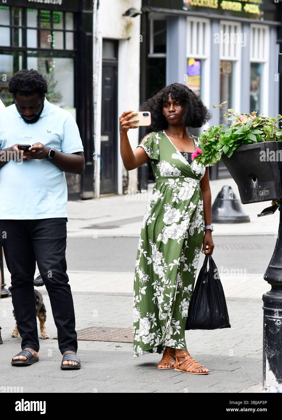 Woman using a smart phone to record a video of street entertainment in Wellington Stock Photo