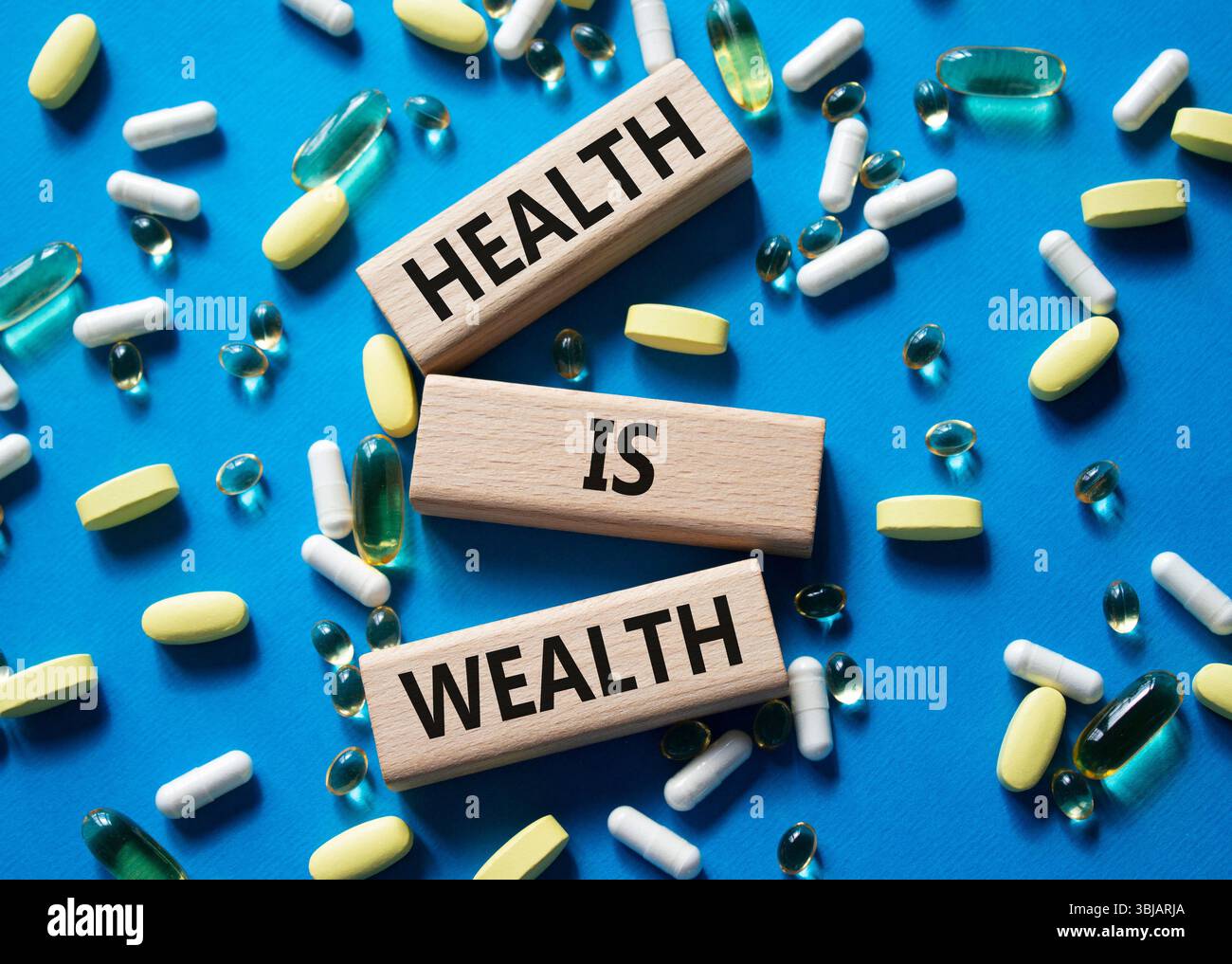 Health is Wealth symbol. Concept word Health is Wealth on wooden blocks. Beautiful blue background with pills. Medicine and Health is Wealth concept. Stock Photo