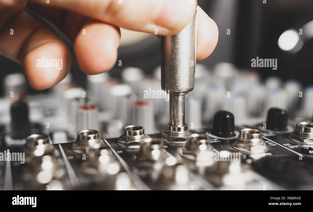 Sound engineer plugging jack audio cable on studio mixer Stock Photo