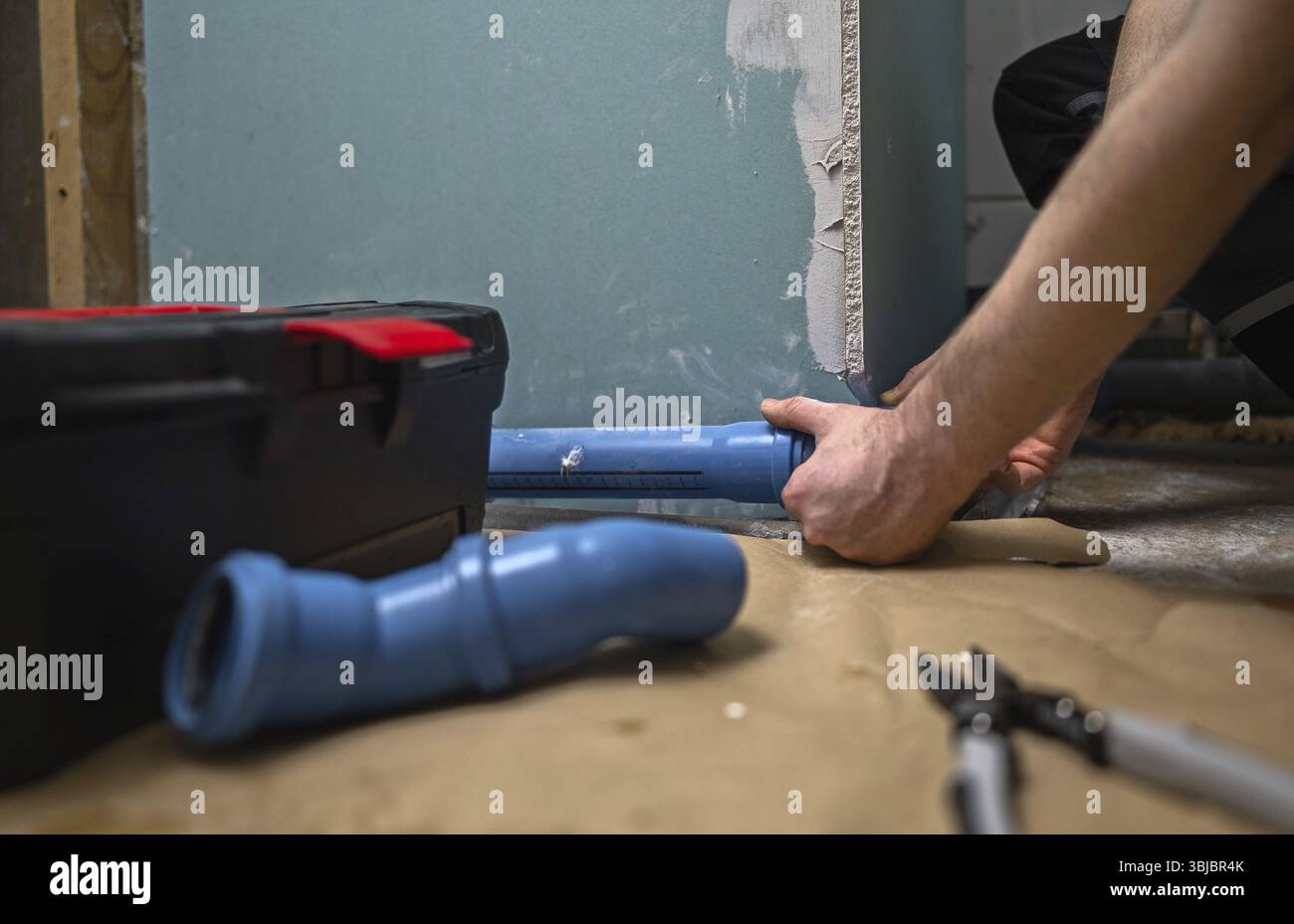Man assembling plumbing pipes in the bathroom Stock Photo