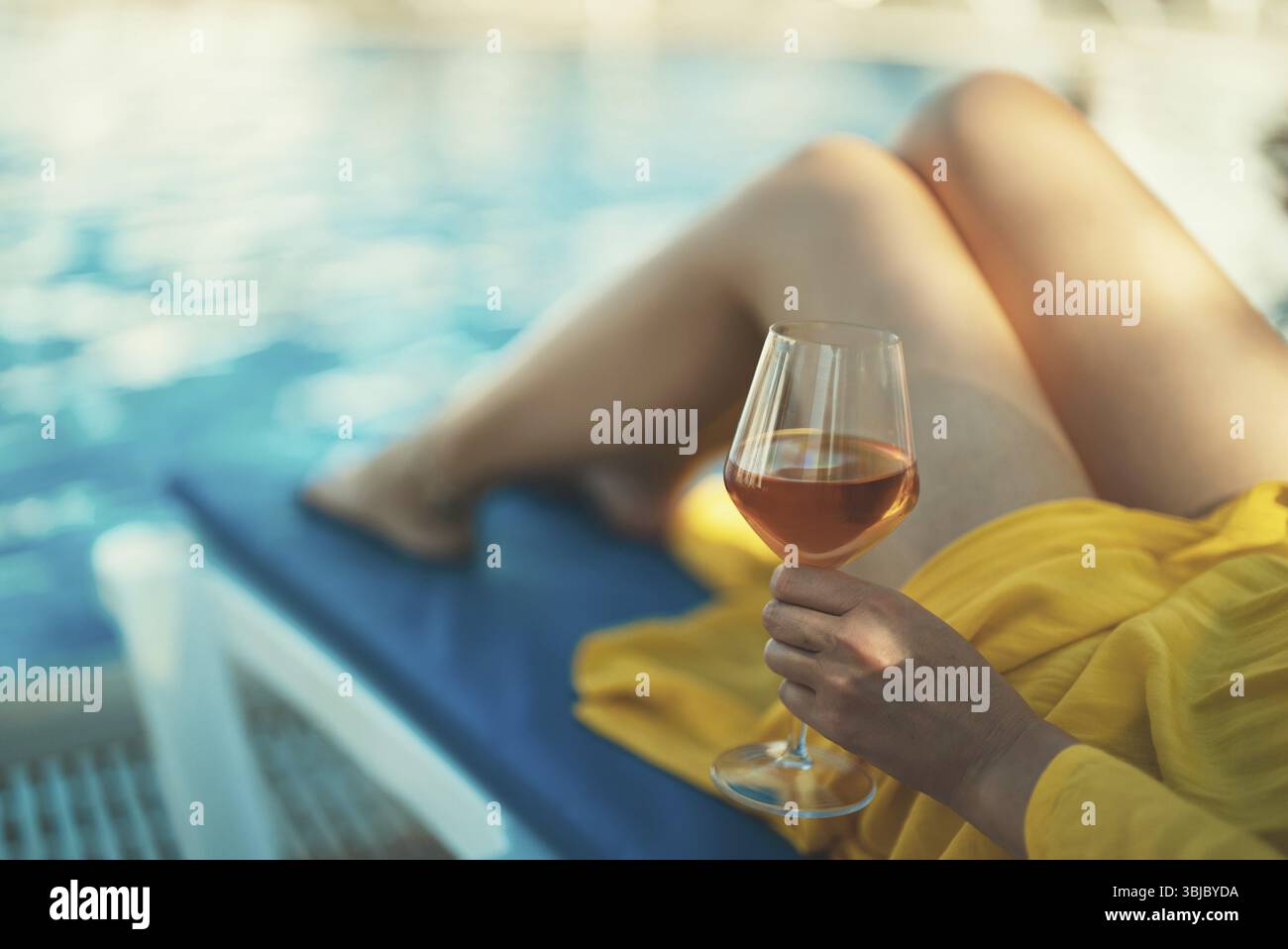 Frau mit Wein, die sich am Swimmingpool entspannt Stock Photo