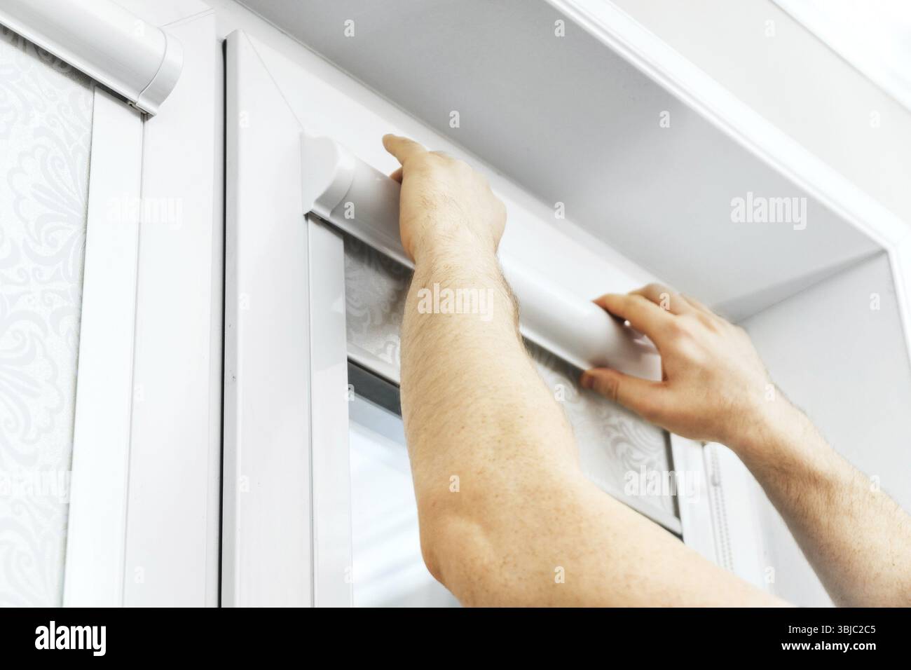 Man installing cassette roller blinds on windows Stock Photo