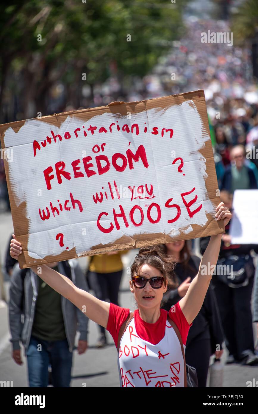 San Francisco, USA. 14th June 2025. At the No Kings Day protest march, with a crowd of thousands filling the street behind her, a woman in red and white holds a sign reading, 'Authoritarianism or FREEDOM, which one will you CHOOSE?' Credit: Shelly Rivoli/Alamy Live News - Stock Image