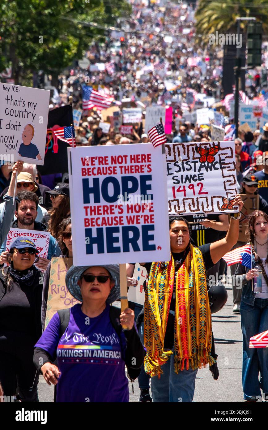 San Francisco, USA. 14th June 2025. With thousands of protesters marching behind her at the No Kings protest, a woman protester holds a sign reading, 'We're not here because there's hope. There's hope because we're here.' Credit: Shelly Rivoli/Alamy Live News - Stock Image