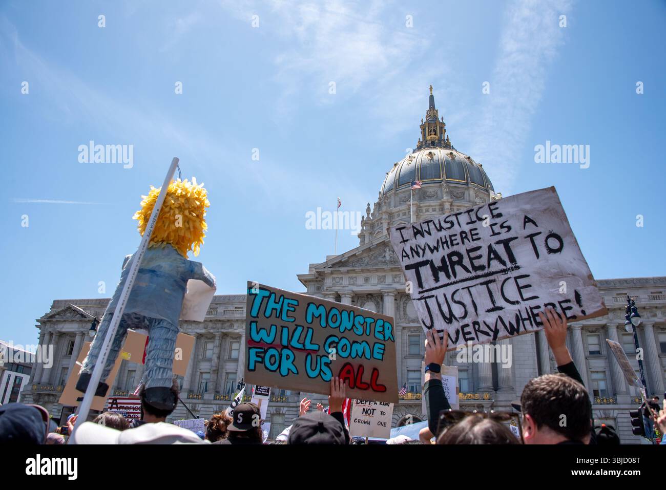 San Francisco, USA. 14th June 2025. Gathering in front of San Francisco City Hall after a march down Market Street, No Kings Day protesters hold signs reading, 'Injustice anywhere is a threat to justice everywhere!' and 'The monster will come for us all,' beside a humorous effigy of Donald Trump.  Credit: Shelly Rivoli/Alamy Live News - Stock Image
