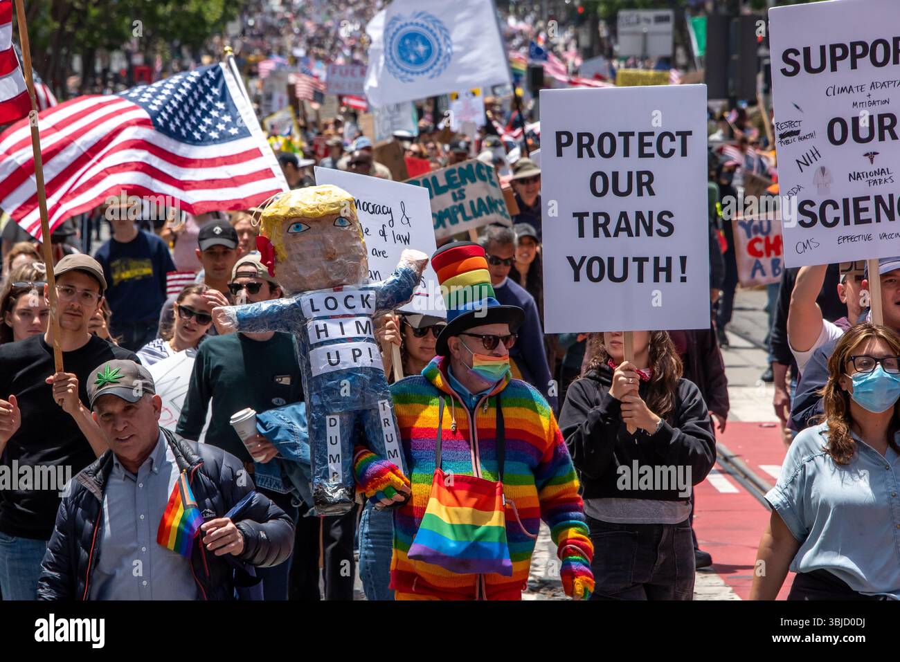 San Francisco, USA. 14th June 2025. WIth thousands of protesters marching down Market Street for the No Kings Day protest event, a man in a rainbow jacket and hat carries an effigy of Donald Trump with the words, 'Lock him up!' on the chest.  Credit: Shelly Rivoli/Alamy Live News - Stock Image