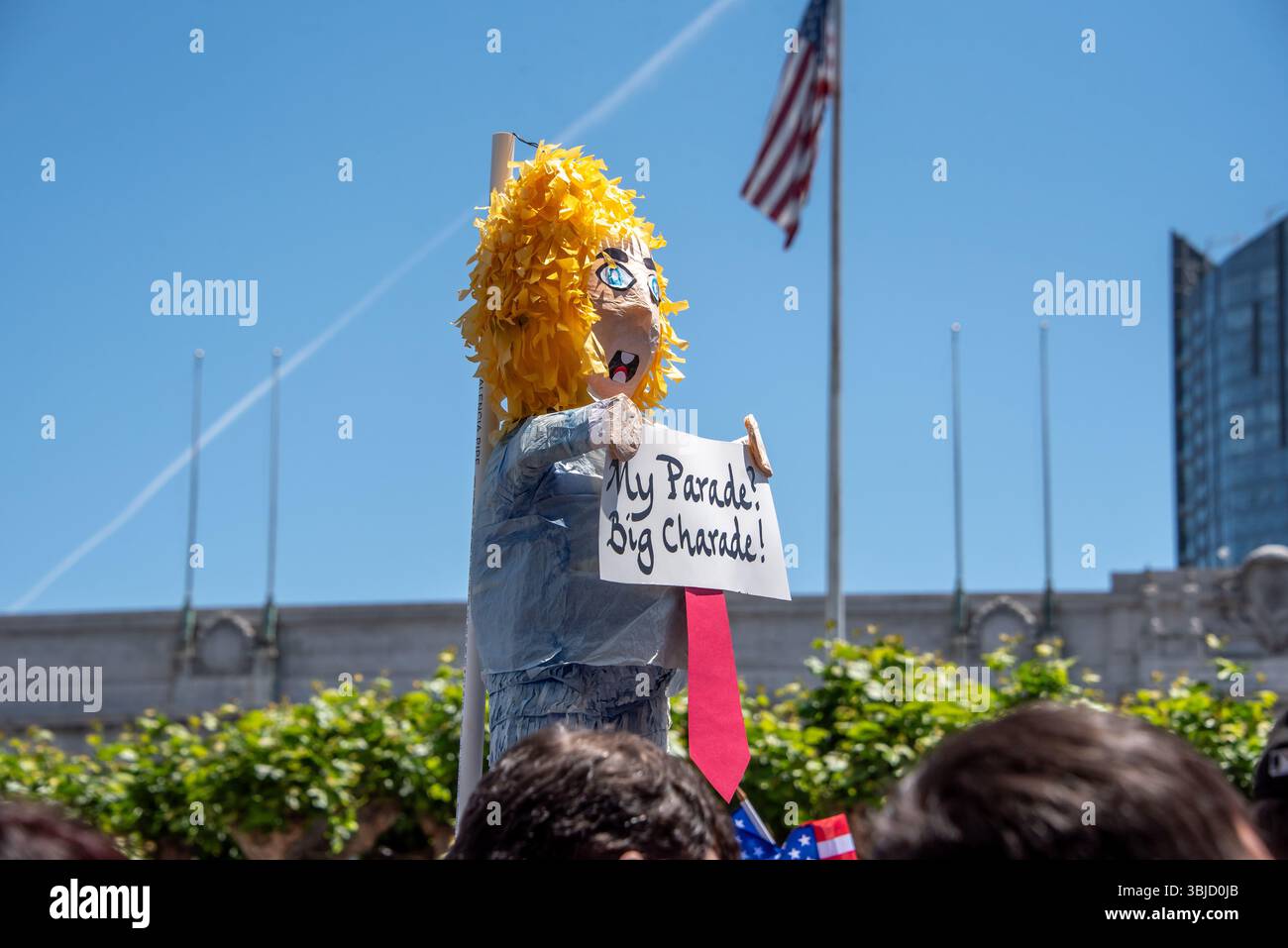 San Francisco, USA. 14th June 2025. Above the protesters gathered for the No Kings Day event in San Francisco, an effigy of Donald Trump wearing a long red tie and holding a sign reading, 'My Parade? Big Charade!' is held high. Trump's military parade is scheduled later in the day. Credit: Shelly Rivoli/Alamy Live News - Stock Image