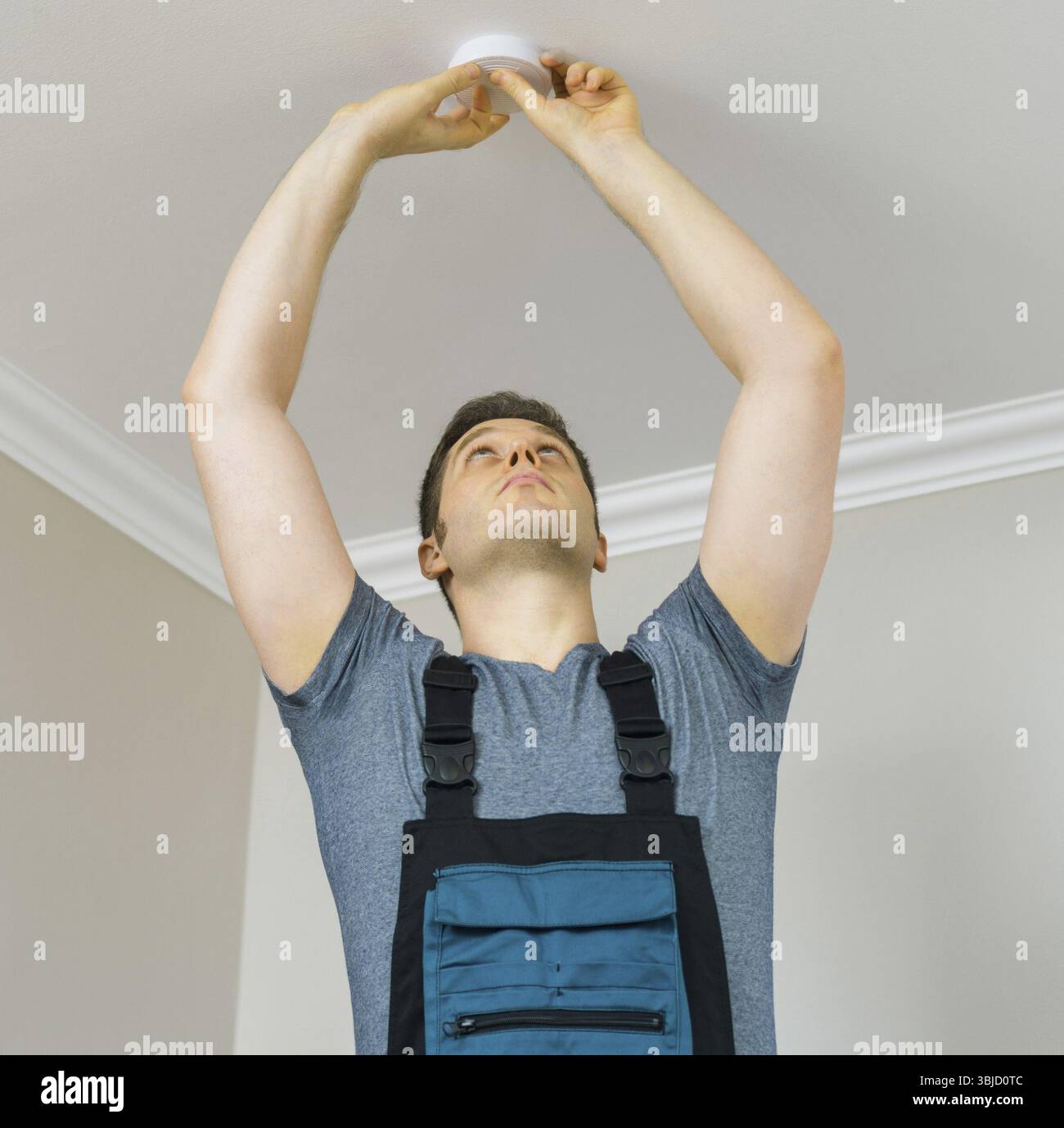 Man mounting smoke detector on the ceiling Stock Photo