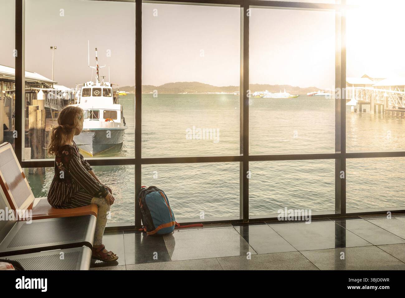 Beautiful zyoung girl waiting for boat in modern dock. Travellng and adventure. Travelling with kids Stock Photo