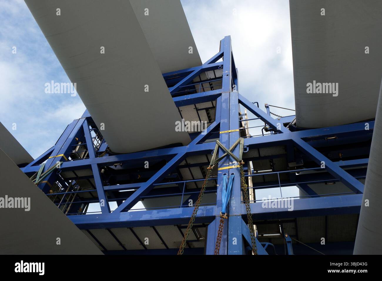 White blades of wind turbine loaded and lashed by slings, chains and ...