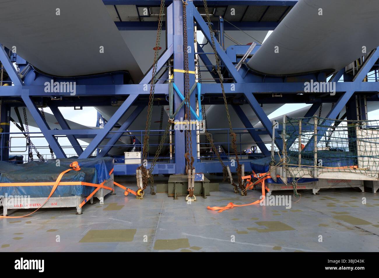 White long blades of wind turbine loaded and lashed by slings, chains ...