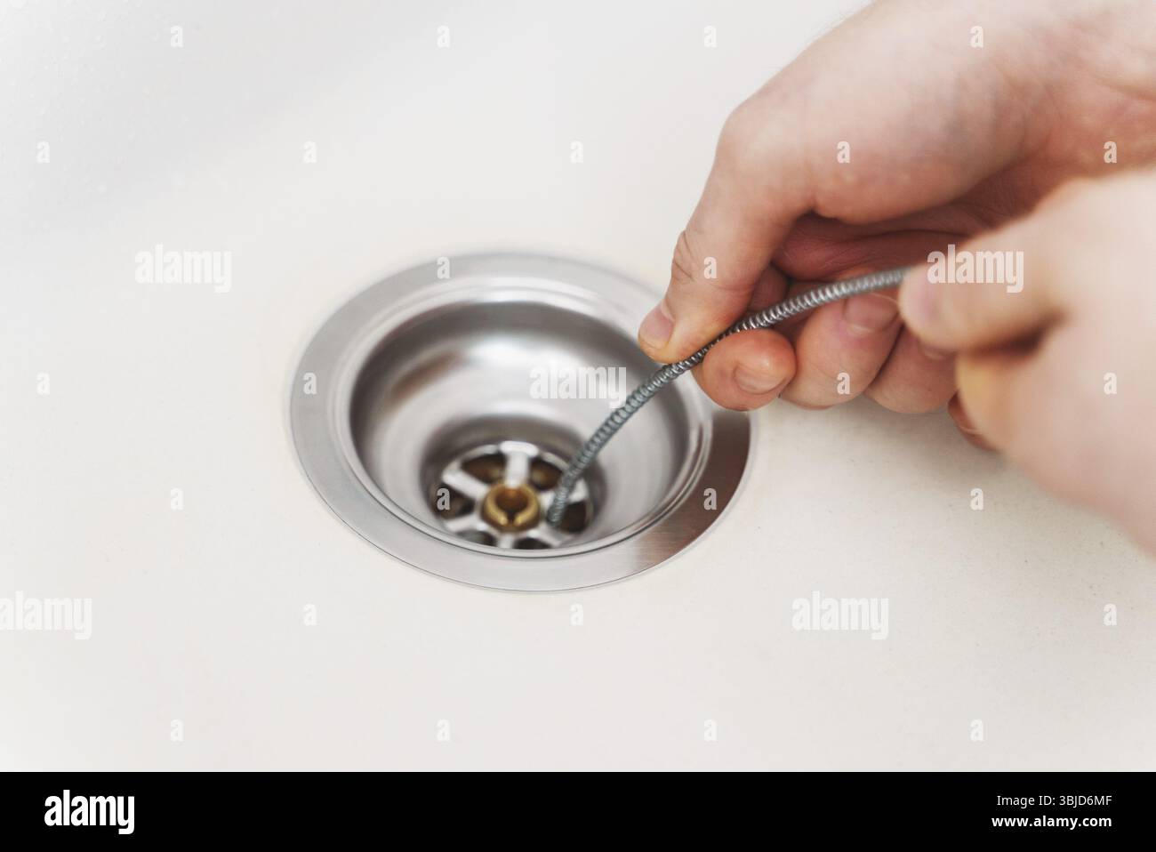 Plumber using drain snake to unclog kitchen sink Stock Photo